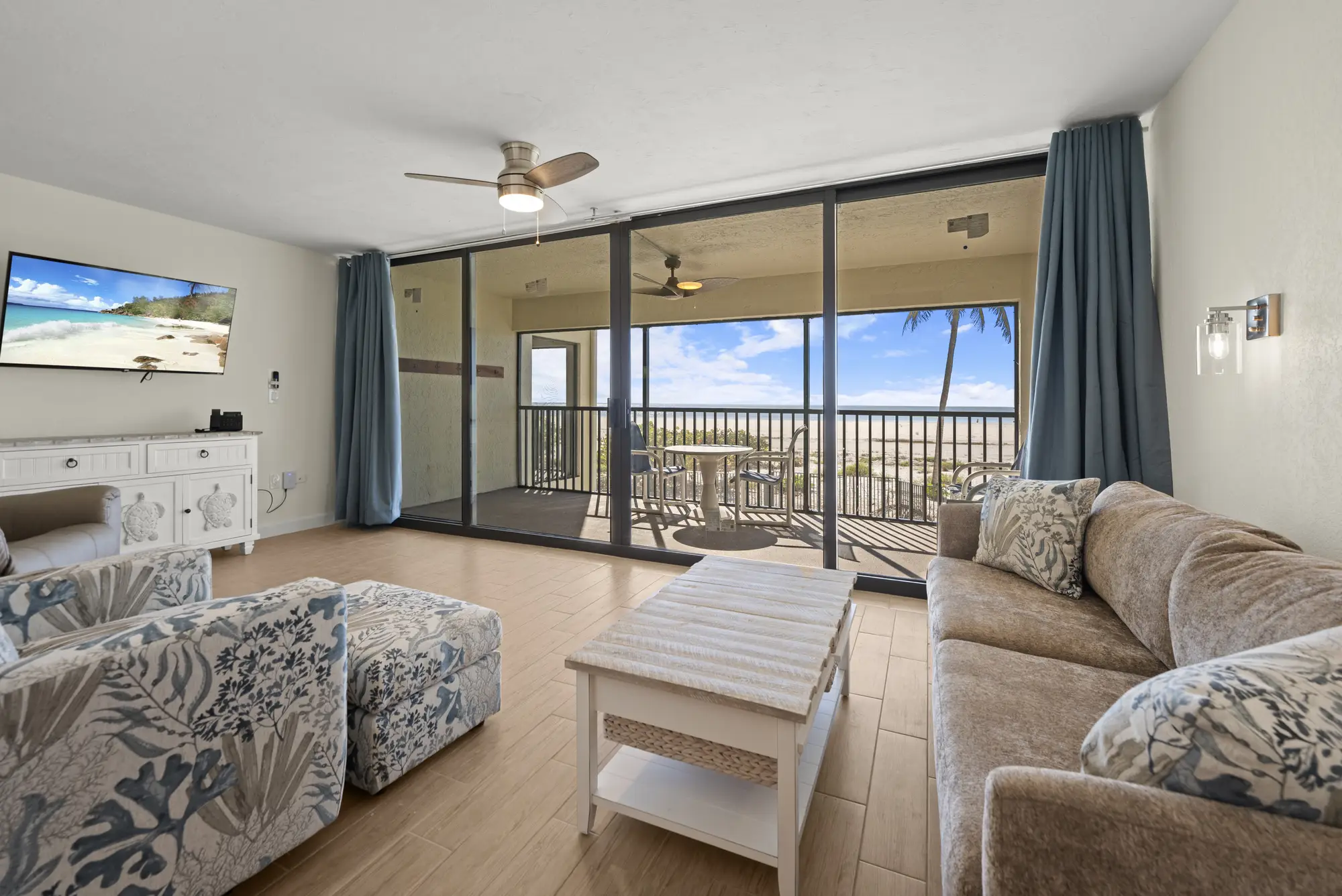 Living room with large sliding doors opening to a balcony with beach and ocean views