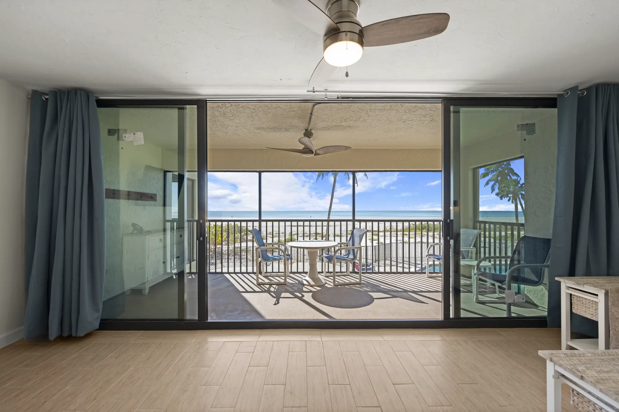 Open living area with sliding glass doors leading to a beachfront balcony with seating.